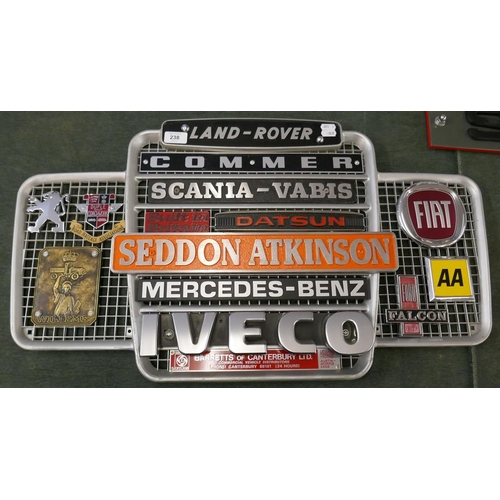 238 - Collection of badges to include Seddon Atkinson, Commer, Mercedes- Benz mounted on a Land Rover gril... 