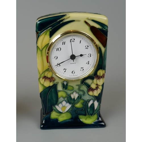 91 - Moorcroft cased small mantel time piece, tube lined with Iris water Lilies on a cream ground. With a... 