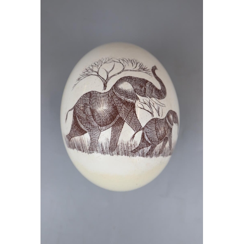 47 - Engraved Ostrich egg on warthog tusk stand - Approx height: 18cm