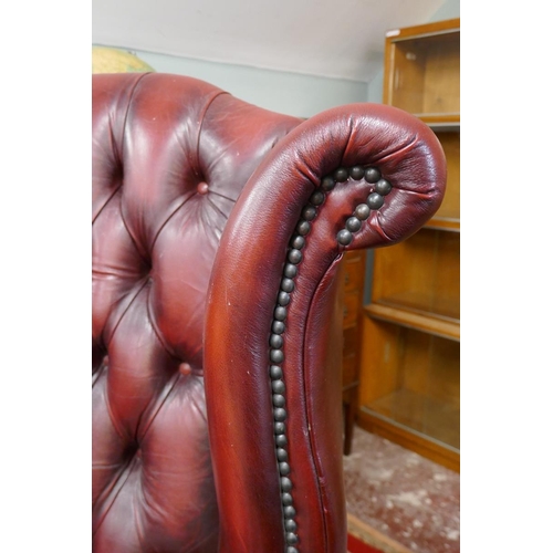 379 - Ox-blood leather wing back chair together with matching stool