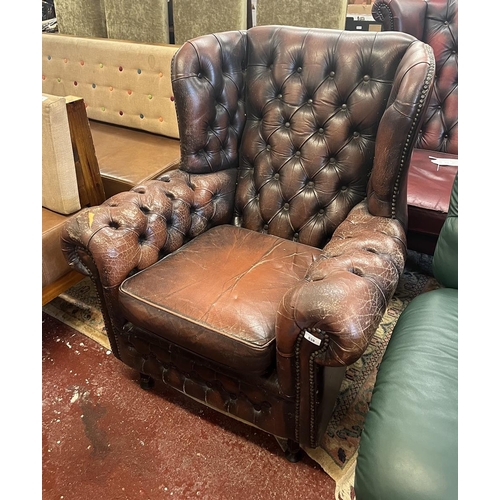 538 - Distressed leather button-back winged armchair