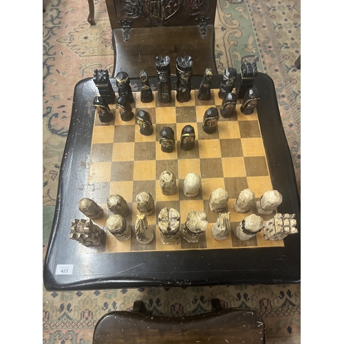 305 - Bespoke carved chess table with 2 matching folding chairs together with carved chess pieces in drawe... 