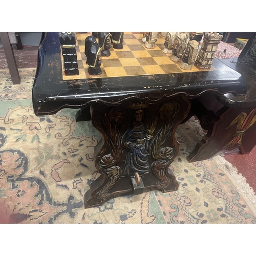 305 - Bespoke carved chess table with 2 matching folding chairs together with carved chess pieces in drawe... 