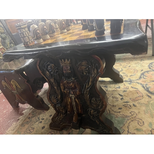 305 - Bespoke carved chess table with 2 matching folding chairs together with carved chess pieces in drawe... 