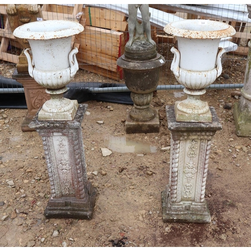 568 - Small pair of cast iron pedestal urns on stone bases