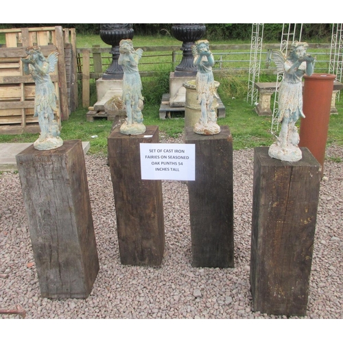 305 - Set a 4 cast iron fairies on seasoned oak plinths - Approx Height: 138cm