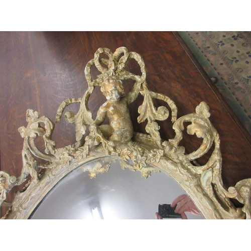 299 - Large early 19thC gilt mirror depicting a rams head at base and seated cherub - Approx Height 108cm