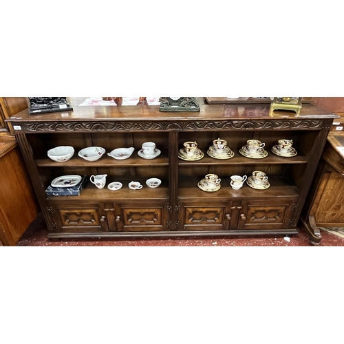 550 - Long open carved oak bookcase with cupboards to base