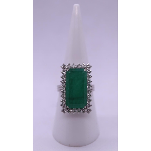 63 - 18ct white gold ring set with large rectangular 10ct emerald bordered by fine diamonds - Size N