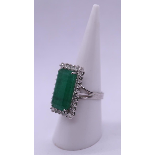 63 - 18ct white gold ring set with large rectangular 10ct emerald bordered by fine diamonds - Size N