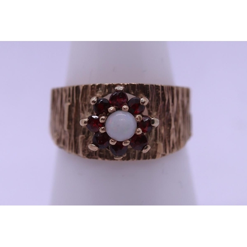 88 - Vintage bark effect 9ct gold ring with central white opal surrounded by 7 garnets. Size O - Approx g... 