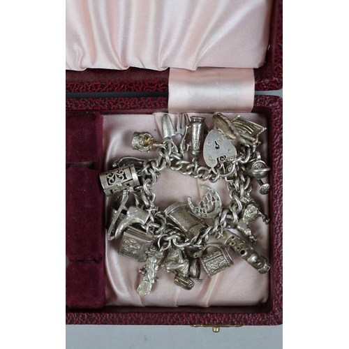 64 - Silver charm bracelet together with a commemorative coin