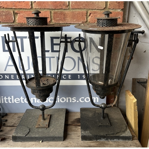 18 - A pair of iron outdoor swinging lamps on stands (glass missing from one)