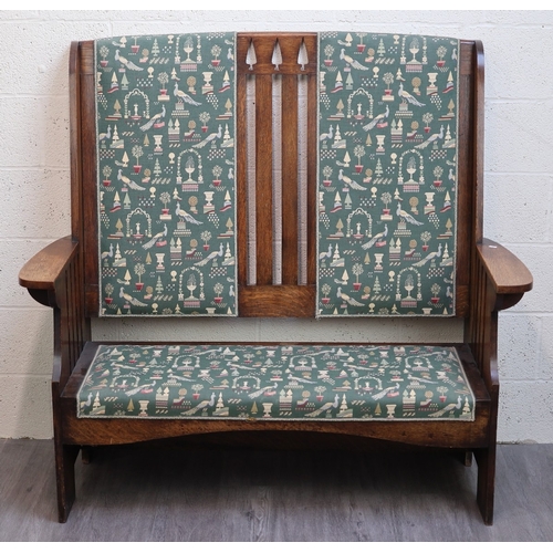 Arts & Crafts oak settle by Liberty & Co with green tapestry upholstery and triple back splat featuring conifer fretwork. Paper label “Liberty & Co., Arts & Crafts Ltd., Shanghai” alludes to the large factory established in 1906 to supply Liberty’s London shop with exclusive oriental items in addition to executing hotel and other Contract Work on the Chinese mainland. A photo from The Cabinet Maker & Complete House Furnisher (SEE hard copy ENCL) depicts Messrs Arts & Crafts, Shanghai, with “Liberty & Co., London” over its entrance portico.