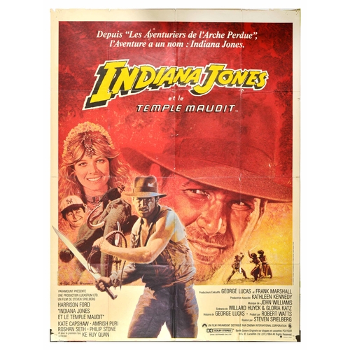 Movie Poster Indiana Jones Temple Doom Harrison Ford. Original vintage cinema poster for the French release of Indiana Jones and the Temple of Doom / Indiana Jones et la Temple Maudit - Artwork by Michel Jouin (1936-2018) features Harrison Ford as the titular character holding a sword and his iconic whip with Kate Capshaw as Willie Scott and Ke Huy Quan as Short Round in the background alongside an elephant. Directed by Stephen Spielberg and written by George Lucas, the film follows Indiana Jones tasked with reclaiming a rock stolen from them by a secret cult beneath the catacombs of an ancient palace. Large size. Fair condition, folds, creasing, tears, pinholes, paper losses. Country of issue: France, designer: Michel Jouin, size (cm): 162x119, year of printing: 1984.