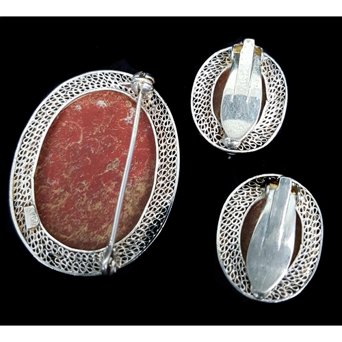 81 - A Silver filigree and cinnabar lacquer oval brooch, the lacquer carved with a flowering peony branch... 