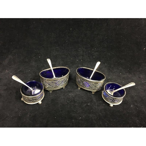 25 - A pair of silver mustard pots, oval with pierced gallery sides on four volute feet, with blue glass ... 