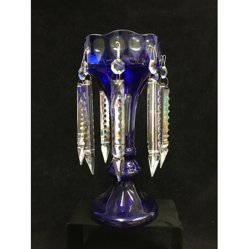 43 - A blue overlay glass lustre, of bud form on trumpet foot, cut through to clear with roundels and flu... 