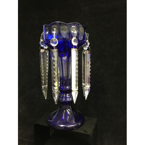 43 - A blue overlay glass lustre, of bud form on trumpet foot, cut through to clear with roundels and flu... 