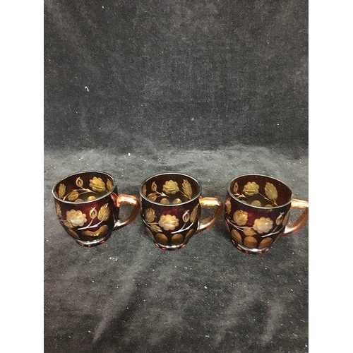 61 - Three bohemian glass punch cups of ruby cut through to amber with flowering vines; and Amberina punc... 