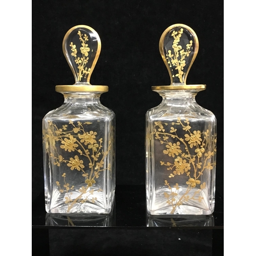 73 - A pair of Baccarat glass perfume bottles and stoppers, colourless glass of square section gilded wit... 