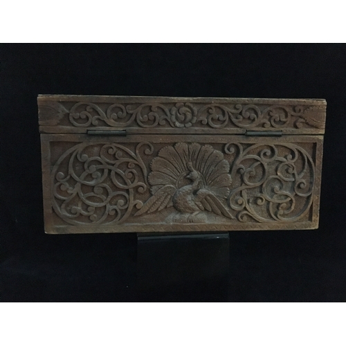 86 - An Indonesian carved wood box, decorated with a panel of figures and a tree within a scrolled border... 