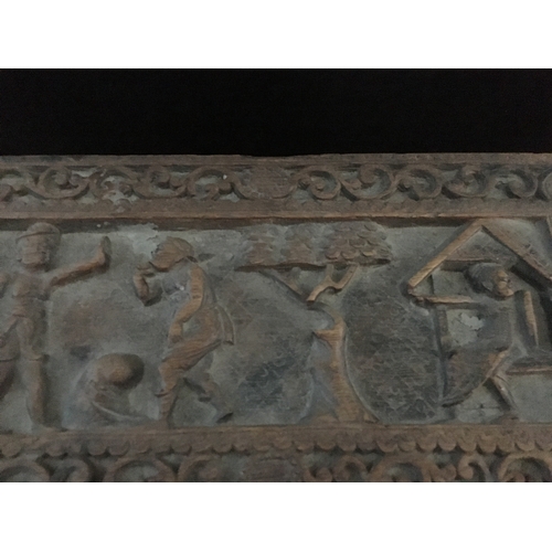 86 - An Indonesian carved wood box, decorated with a panel of figures and a tree within a scrolled border... 