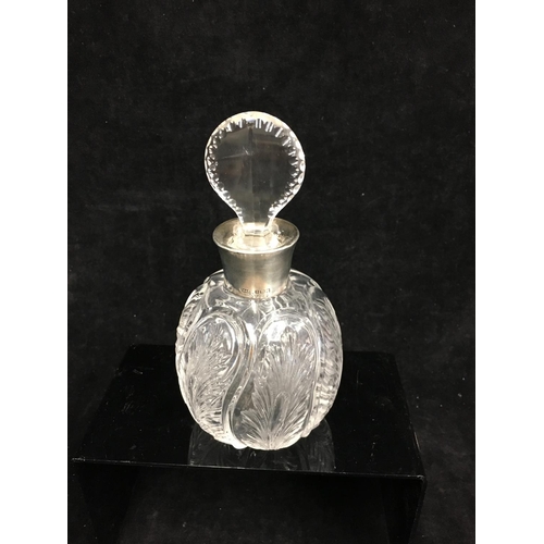 88 - A silver topped cut glass perfume bottle, in rock crystal style, the ovoid body cut with leaf motifs... 