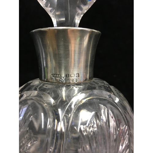 88 - A silver topped cut glass perfume bottle, in rock crystal style, the ovoid body cut with leaf motifs... 