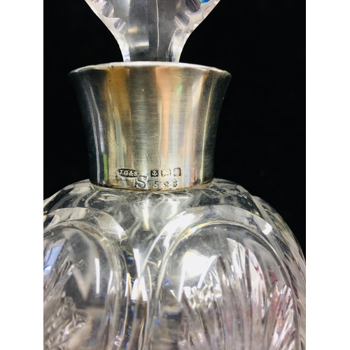 88 - A silver topped cut glass perfume bottle, in rock crystal style, the ovoid body cut with leaf motifs... 