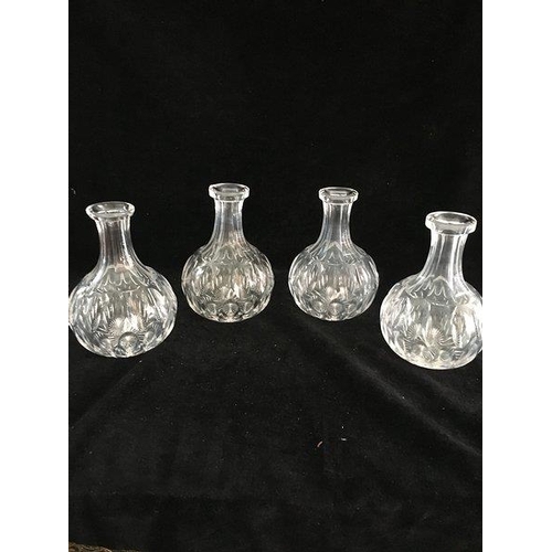 141 - A set of four cut glass water carafes, each of bottle form cit with rows of ovoid reserves, 16cm hig... 