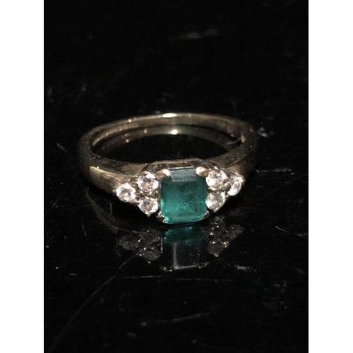 14 - An emerald and diamond set child's ring, the central synthetic emerald 4.64 x 3.85 approx split claw... 