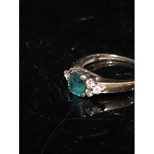 14 - An emerald and diamond set child's ring, the central synthetic emerald 4.64 x 3.85 approx split claw... 