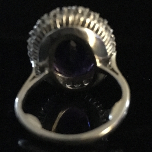 26 - An amethyst and diamond cluster ring, the oval trap cut deep amethyst stone measuring 17.84mm x 13.1... 