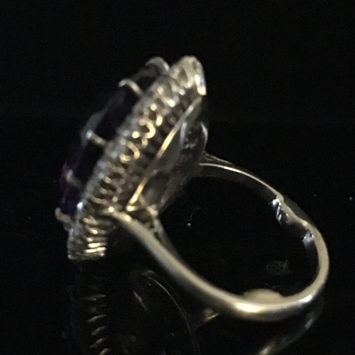 26 - An amethyst and diamond cluster ring, the oval trap cut deep amethyst stone measuring 17.84mm x 13.1... 