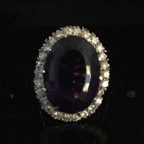 26 - An amethyst and diamond cluster ring, the oval trap cut deep amethyst stone measuring 17.84mm x 13.1... 