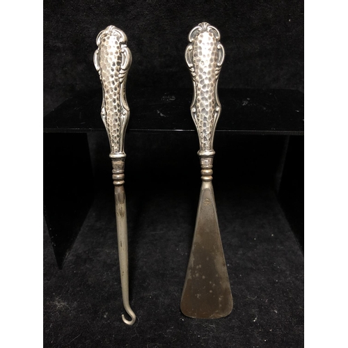 30 - A shoe horn and button hook, steel each with silver handles of plannished work within 'C' scrolls, B... 