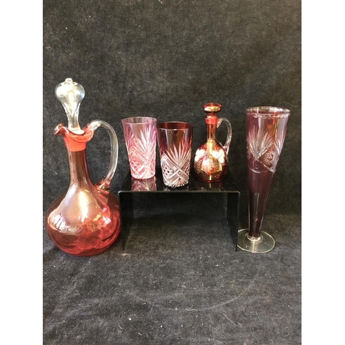 135 - A group of ruby and cranberry coloured glass ware comprising a cranberry claret jug; two cut beakers... 