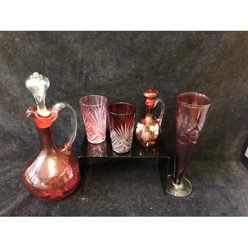 135 - A group of ruby and cranberry coloured glass ware comprising a cranberry claret jug; two cut beakers... 