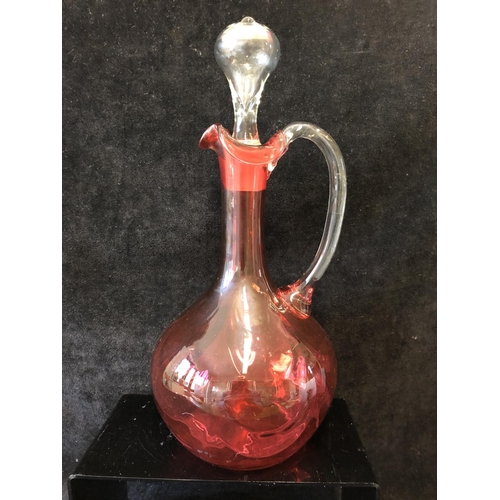 135 - A group of ruby and cranberry coloured glass ware comprising a cranberry claret jug; two cut beakers... 