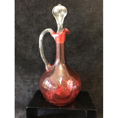 135 - A group of ruby and cranberry coloured glass ware comprising a cranberry claret jug; two cut beakers... 