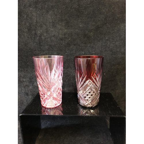 135 - A group of ruby and cranberry coloured glass ware comprising a cranberry claret jug; two cut beakers... 