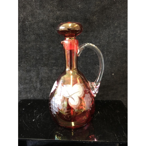 135 - A group of ruby and cranberry coloured glass ware comprising a cranberry claret jug; two cut beakers... 