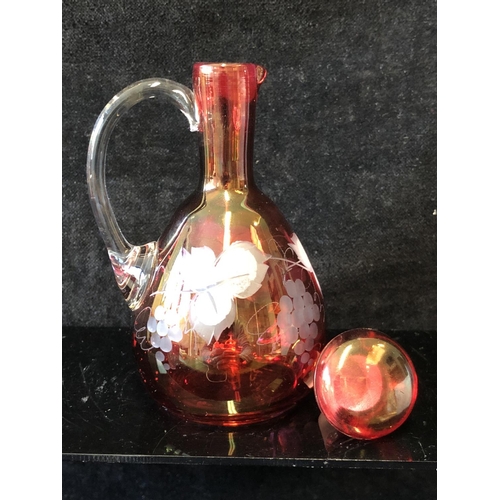 135 - A group of ruby and cranberry coloured glass ware comprising a cranberry claret jug; two cut beakers... 