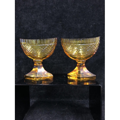 52 - Bohemian Glass - A pair of amber glass boat form pedestal salts, cut with hobnail banding and dentil... 