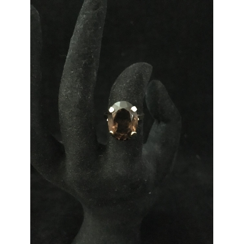 239 - A 9ct yellow gold dress ring, set with a chocolate coloured oval facetted stone, ring size M 1/2, to... 