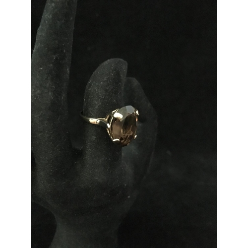 239 - A 9ct yellow gold dress ring, set with a chocolate coloured oval facetted stone, ring size M 1/2, to... 