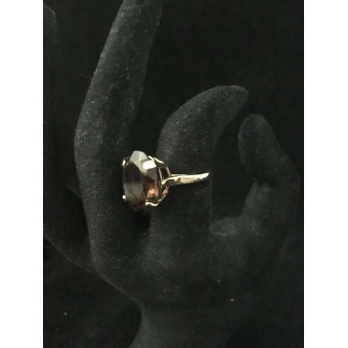 239 - A 9ct yellow gold dress ring, set with a chocolate coloured oval facetted stone, ring size M 1/2, to... 