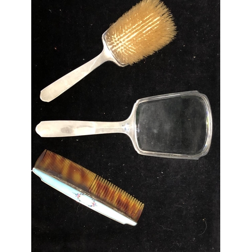 5 - An Enamelled silver dressing table set, comprises hand mirror, handled brush and comb, engine turned... 