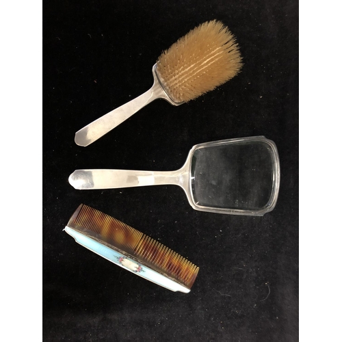 5 - An Enamelled silver dressing table set, comprises hand mirror, handled brush and comb, engine turned... 